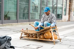 Un musicien joue du balafon avec deux mailloches, lames de bois posées sur des calebasses résonantes
