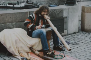 Un musicien joue du didgeridoo, instrument à vent long et conique, en extérieur