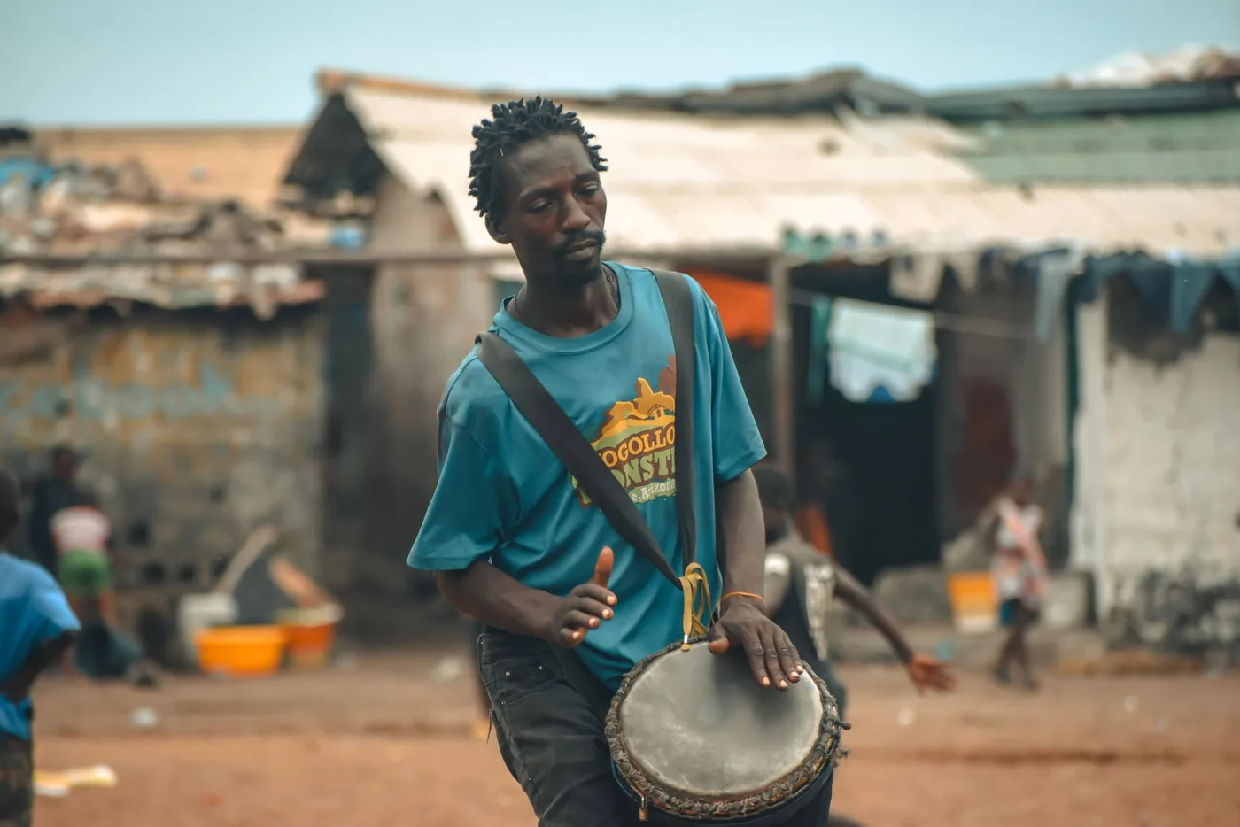 Un homme marche dans une rue de Monrovia en jouant du djembé porté en bandoulière