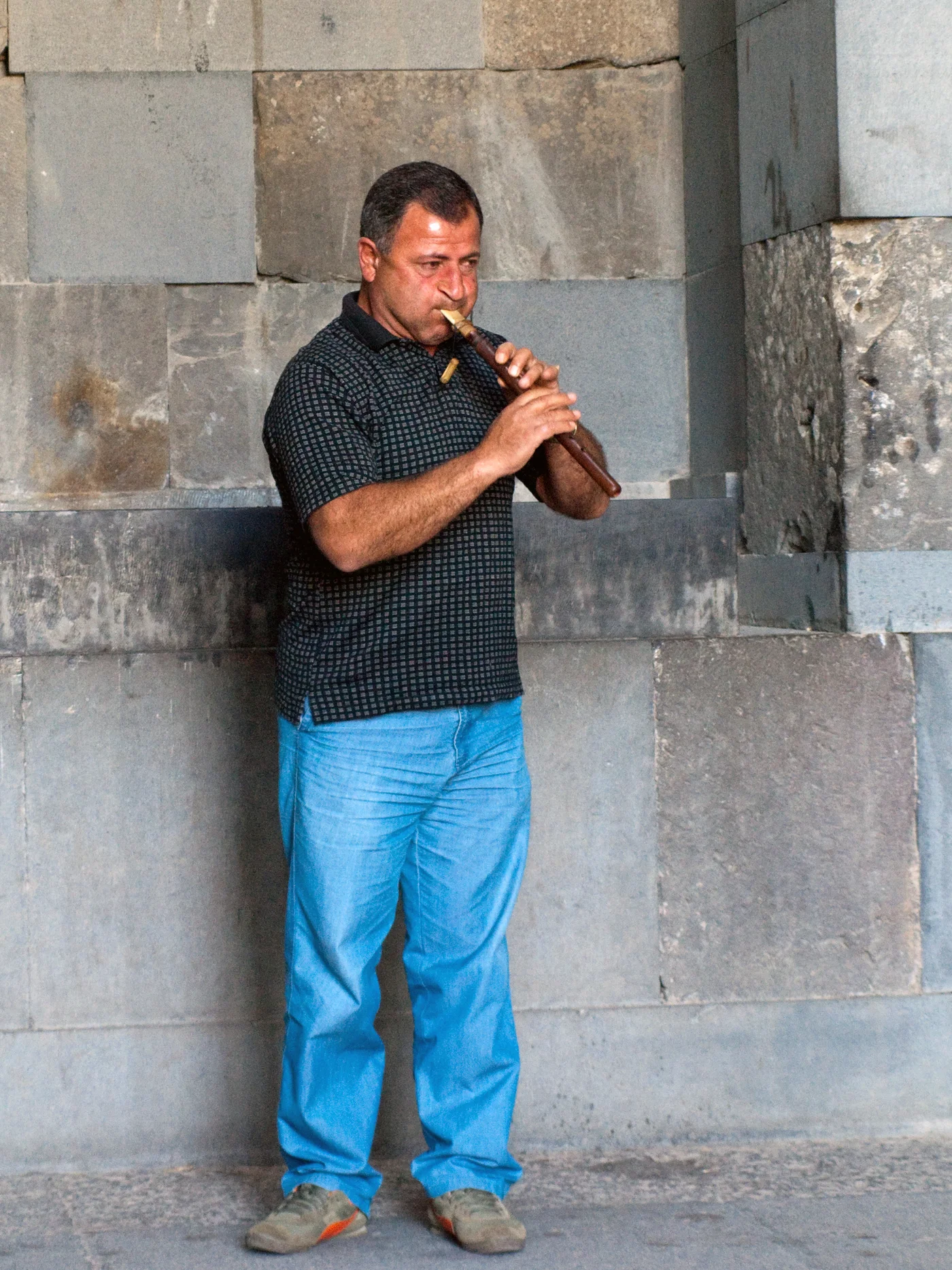 Un musicien joue du duduk devant les pierres du temple de Garni, en Arménie