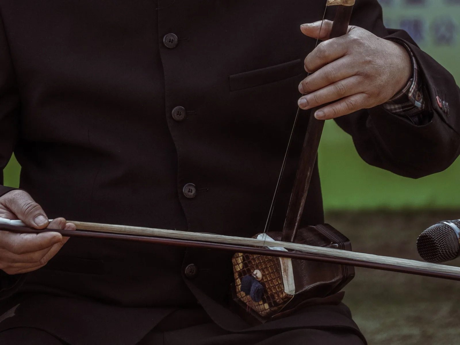 Gros plan sur la caisse hexagonale d'un erhu et sur l'archet dont les crins passent entre les deux cordes de l'instrument