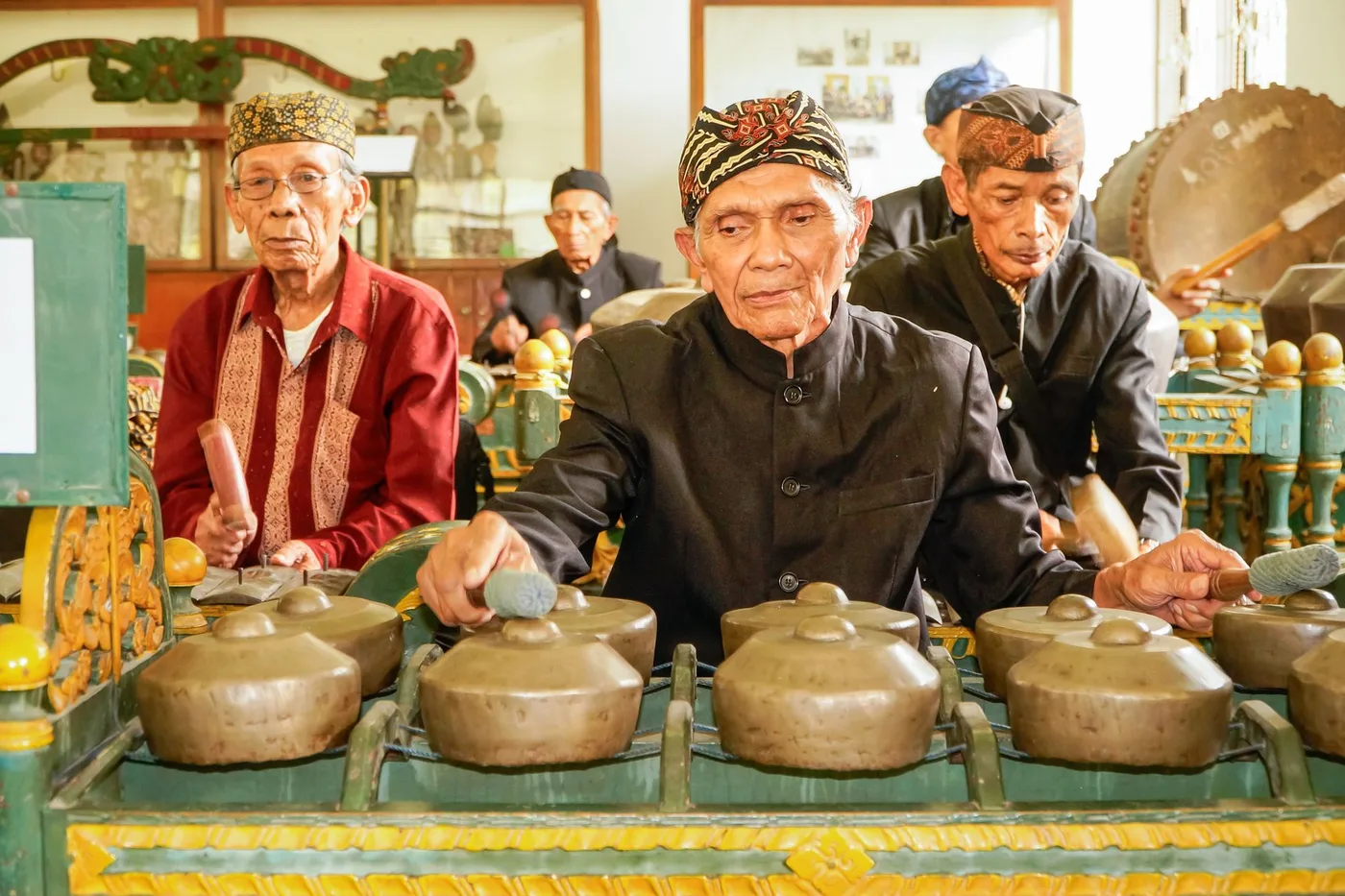 Musiciens jouant les gongs en forme de bols du bonang d une gamelan javanais, avec un grand gong suspendu en arriere-plan