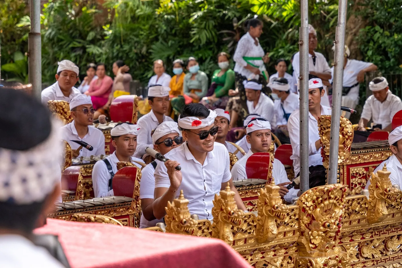 Musiciens d'un gamelan balinais aux cadres de bois dorés jouant lors d'une cérémonie en extérieur