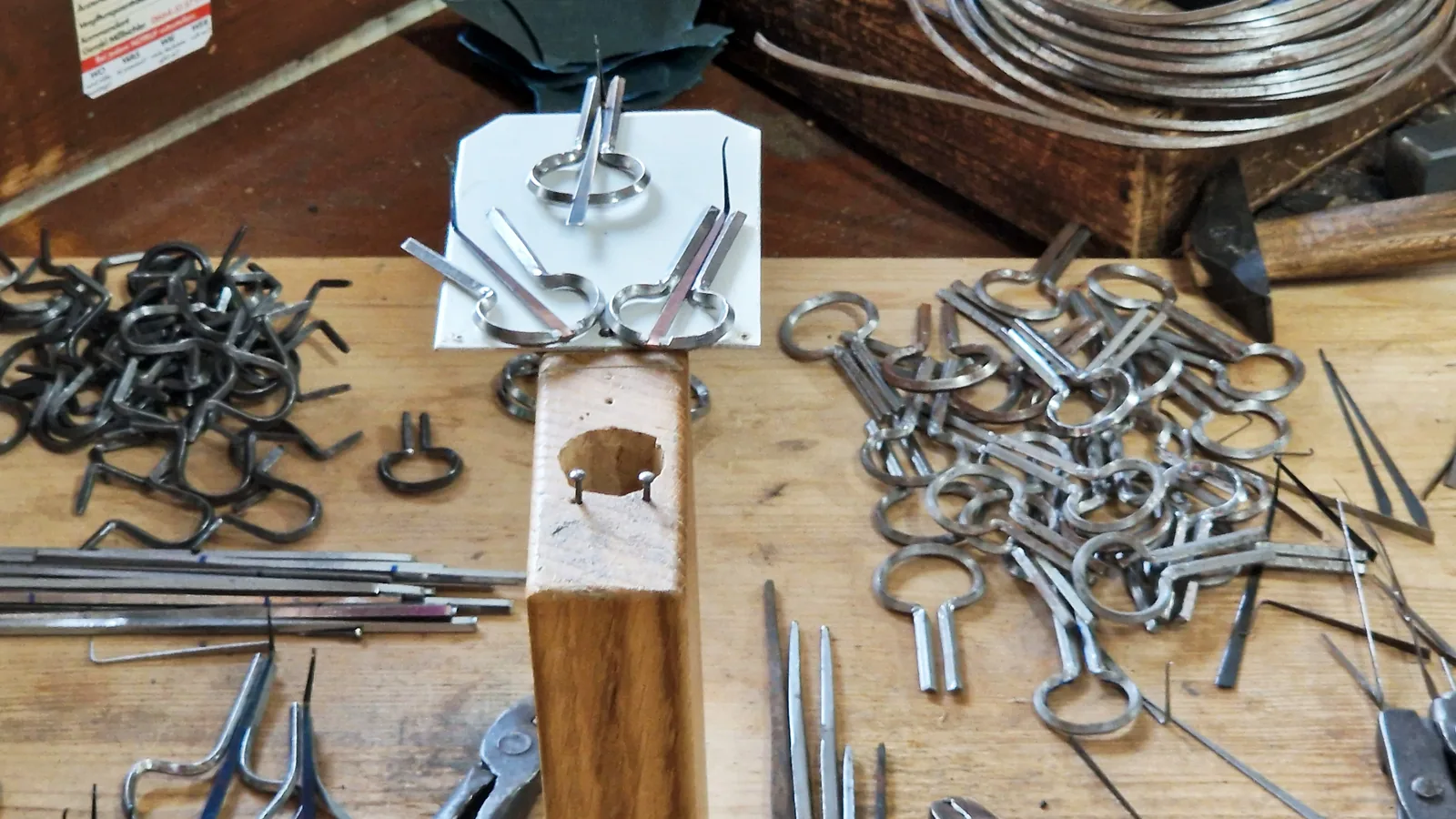 Cadres et languettes de guimbardes en métal brut, à différents stades de fabrication, sur un établi d'atelier en Autriche