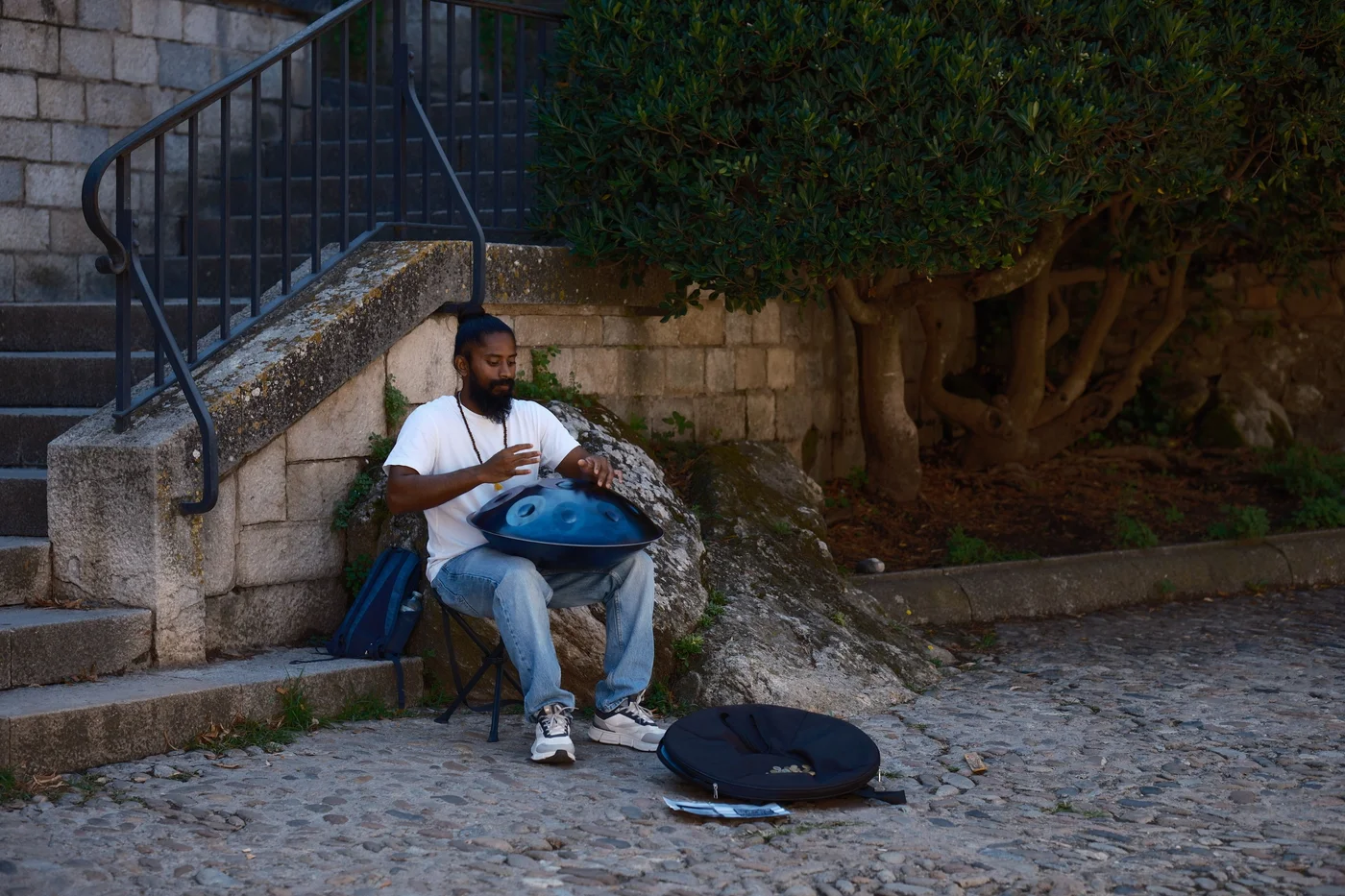 Un musicien de rue joue du handpan posé sur ses genoux en pleine ville