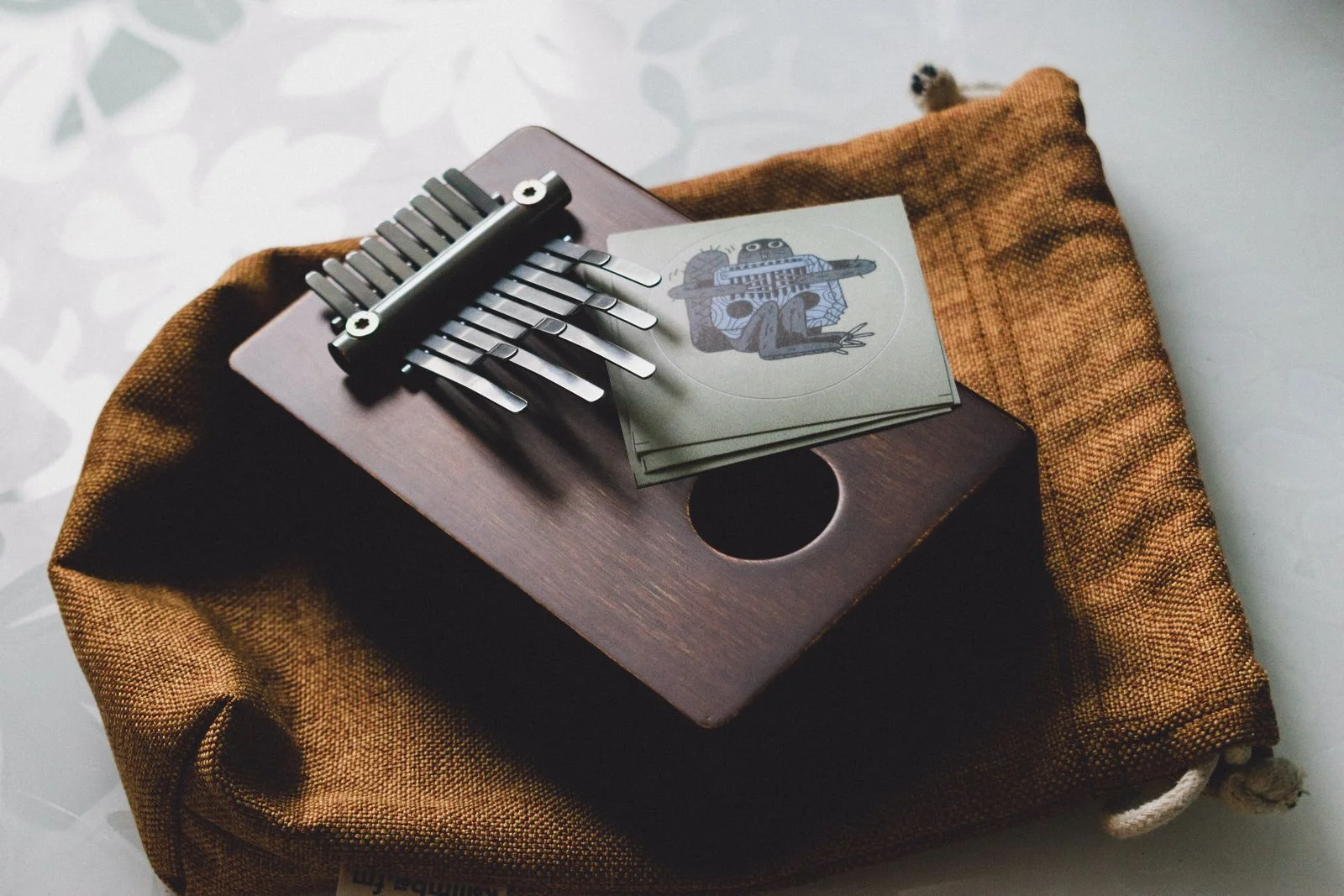 Gros plan sur les lamelles métalliques d'un kalimba en bois posé sur une pochette de rangement