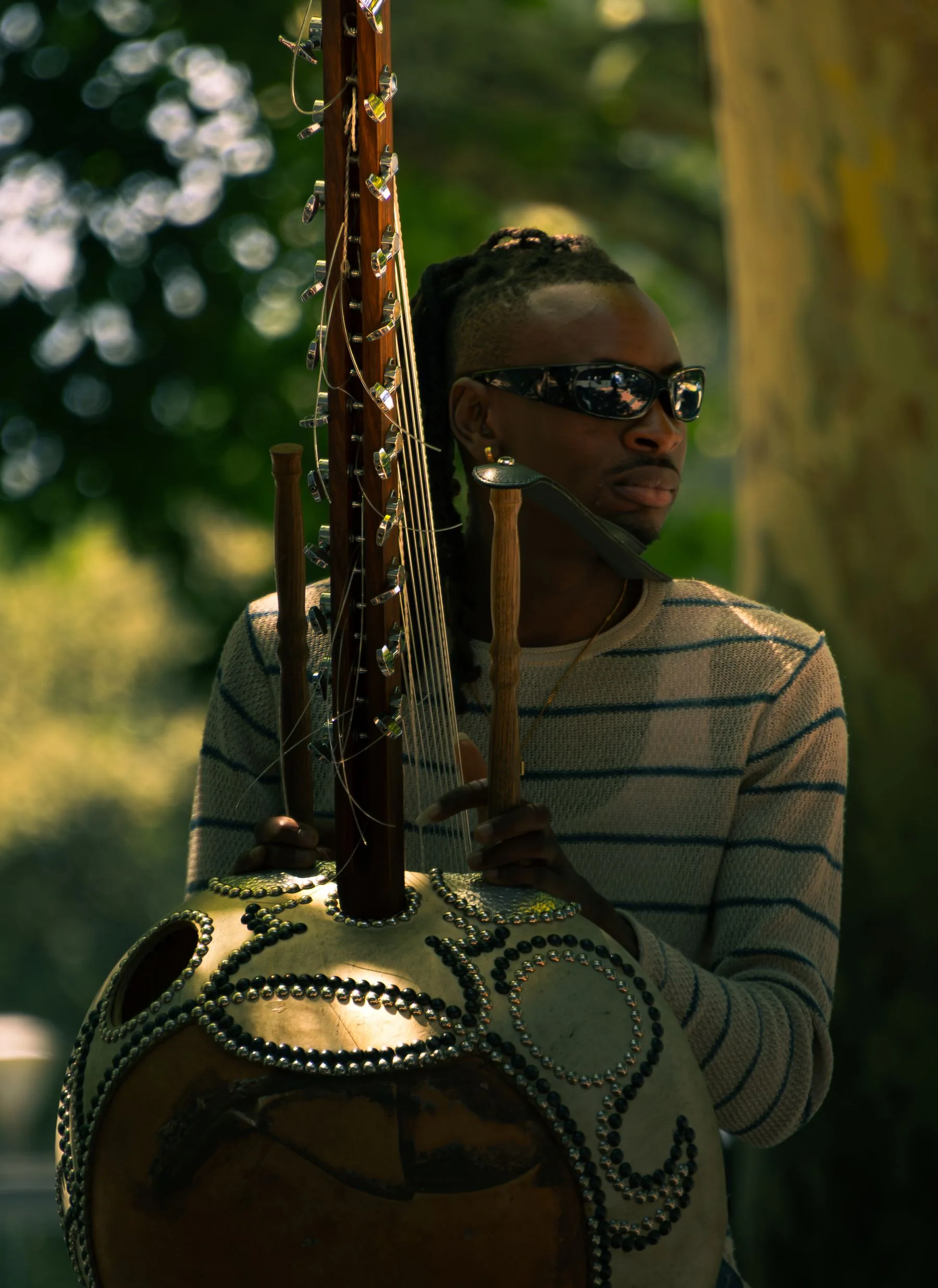 Un musicien tient une kora, grande calebasse décorée et long manche à chevilles mécaniques