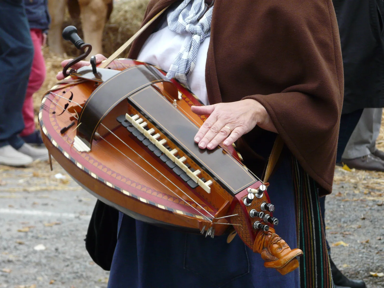 Vielle à roue tenue par un musicien, clavier de touches et manivelle visibles en gros plan